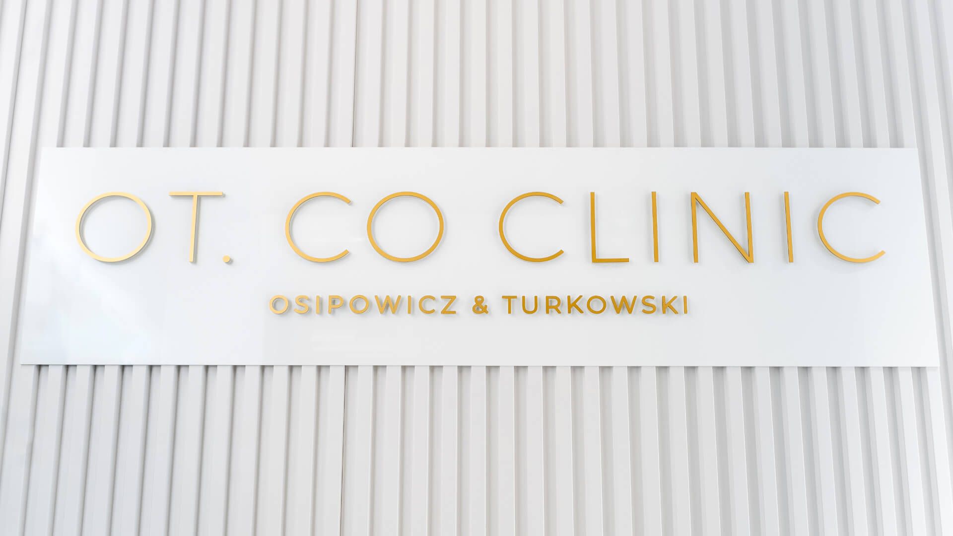 Wandbuchstaben OT.CO Klinik - Goldene Prismenbuchstaben an der Wand im Empfangsbereich der OT.CO Klinik