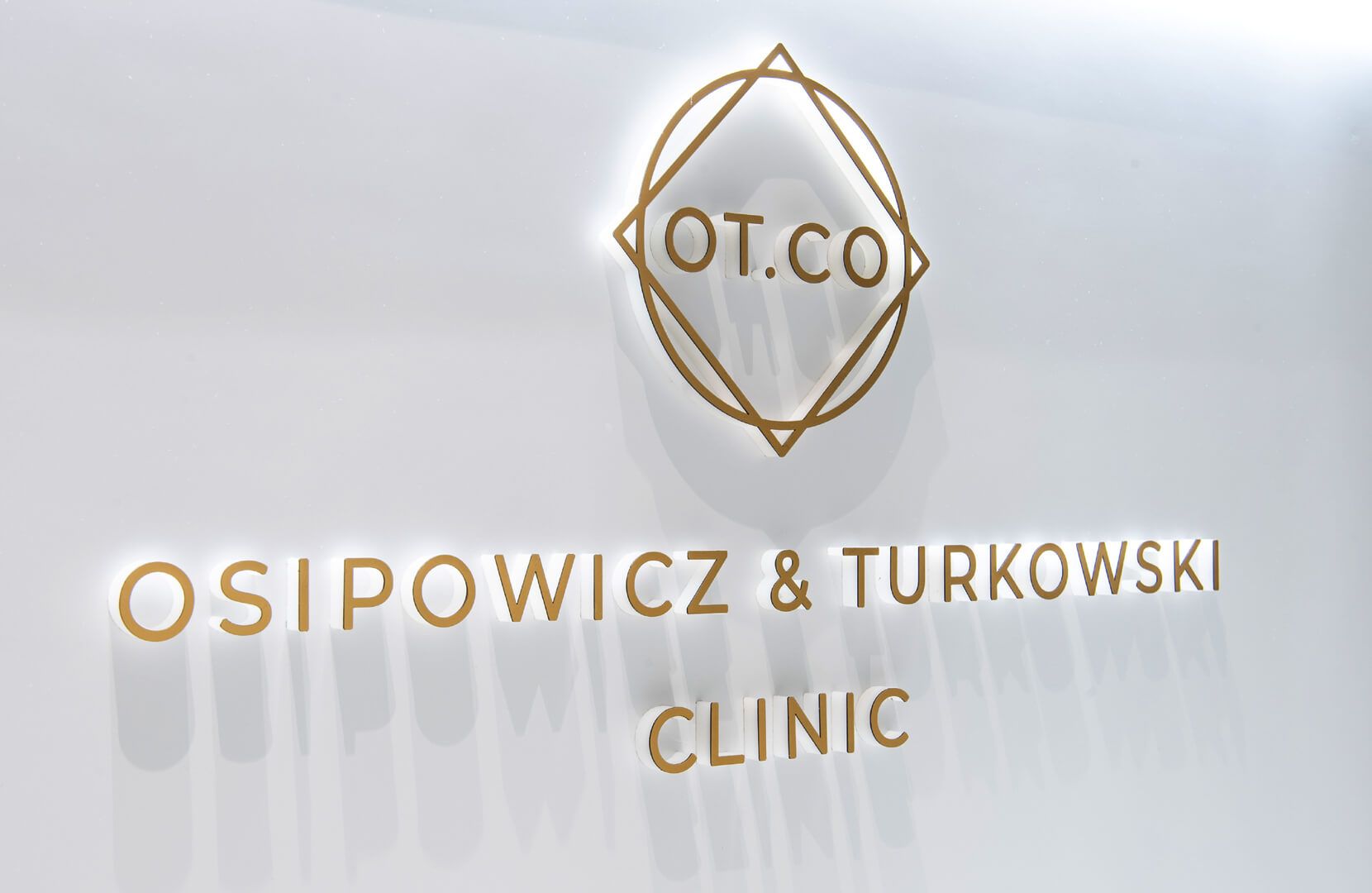 Raumbuchstaben im Empfangsbereich der OT.CO Klinik - Goldene Raumbuchstaben mit Logo im Empfangsbereich der OT.CO Klinik